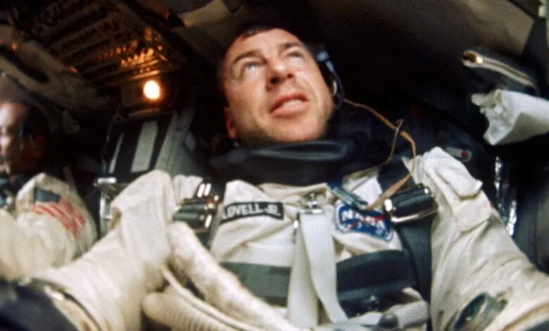 Close-up of astronaut James Lovell aboard Apollo 8, wearing a spacesuit and headset, inside a spacecraft.
