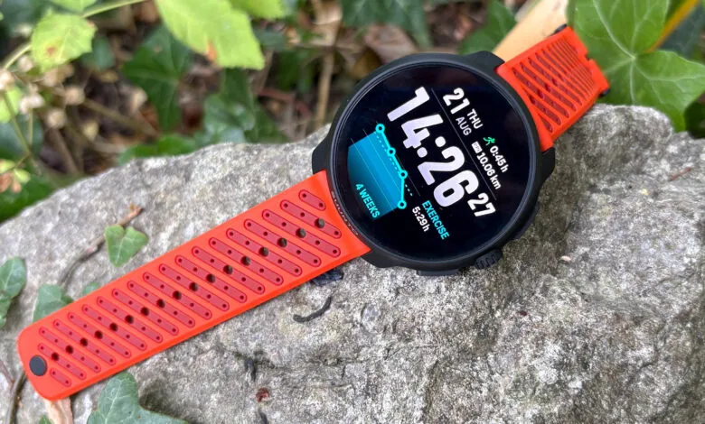 Orange Suunto sports watch with a detailed display resting on a textured rock.