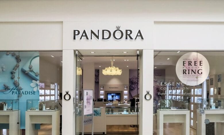 Pandora jewelry store storefront with display showcasing rings and charms. A sign advertises a free ring with purchase.