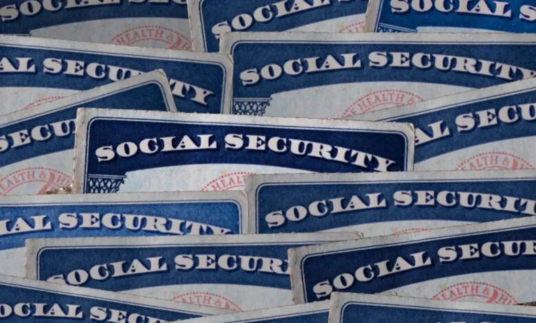 Close-up of numerous Social Security cards overlapping, showing the blue and white design and text.