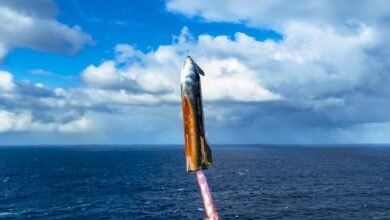 SpaceX Starship rocket launch over ocean, fiery exhaust trail visible against a partly cloudy sky.