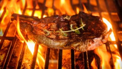 A juicy steak, seasoned with thyme, sizzles on a fiery grill.