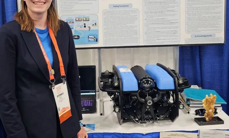 Smiling scientist Sydney presents her remotely operated underwater vehicle (ROV) and coral research project at a science fair.