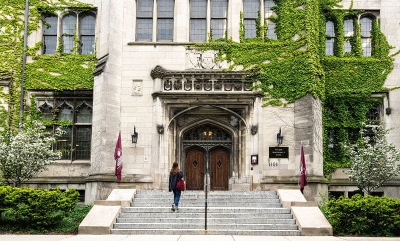A student walks up the steps to Julius Rosenwald Hall at the University of Chicago, a building covered in ivy.
