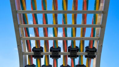 Colorful cables secured on a metal rack against a bright blue sky.