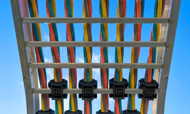 Colorful cables secured on a metal rack against a bright blue sky.