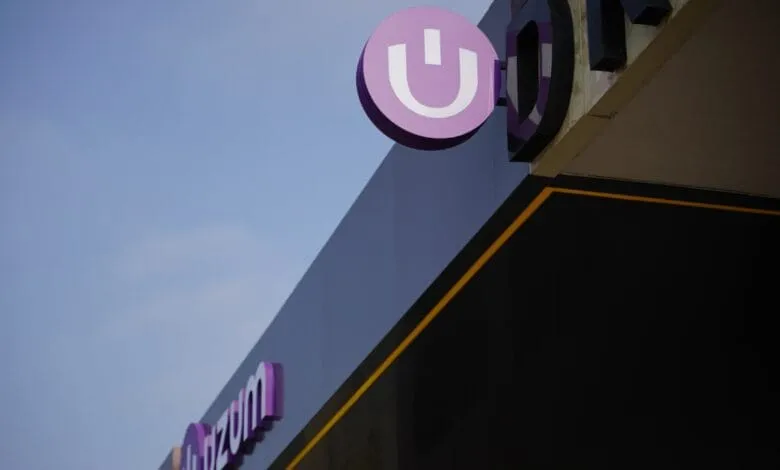 Uzom logo on a building exterior, purple and white branding against a dark background.