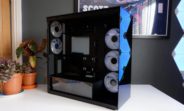 Sleek black computer case with blue LED lighting, showcasing internal components and fans. Plants sit on the table beside it.