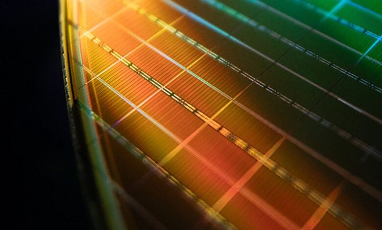 Close-up of a microchip's intricate circuitry, showcasing a grid pattern in warm orange and cool green hues.