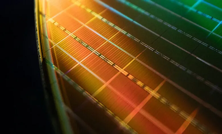 Close-up of a microchip's intricate circuitry, showcasing a grid pattern in warm orange and cool green hues.