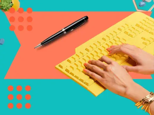 Hands typing on a yellow keyboard, a pen rests nearby. Colorful background.