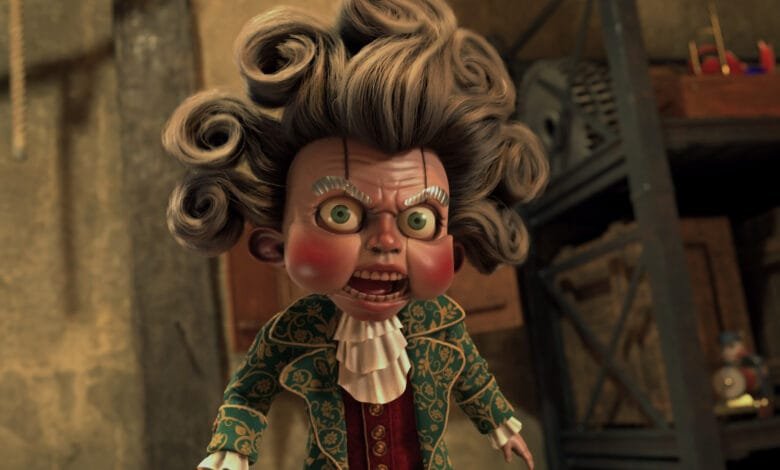 Close-up of an angry puppet with large curly hair, wearing a green and gold coat.