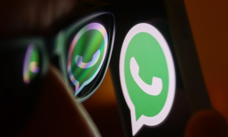 Close-up of a smartphone displaying the WhatsApp logo, reflected in eyeglasses.