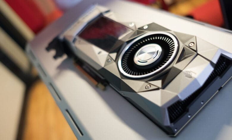 Close-up of a sleek, gray and black graphics card with a prominent cooling fan, resting on a light gray surface.