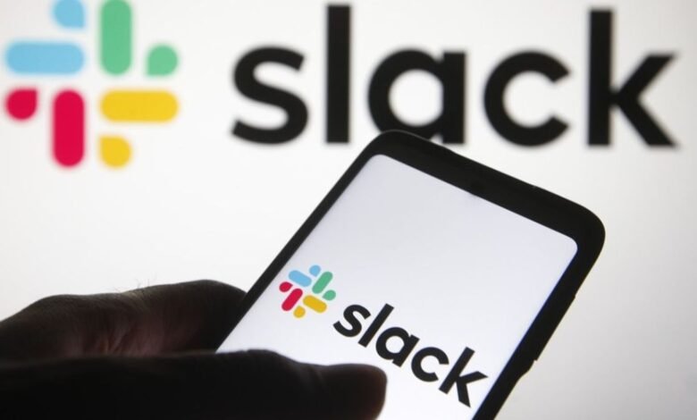 Close-up of a smartphone displaying the Slack logo and app, with the larger Slack logo blurred in the background.