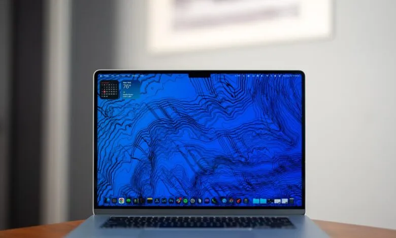 macOS laptop displaying a blue topographic map desktop wallpaper.