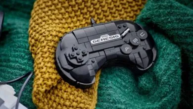 Black LEGO Sega Genesis controller on mustard yellow and teal knit fabric.
