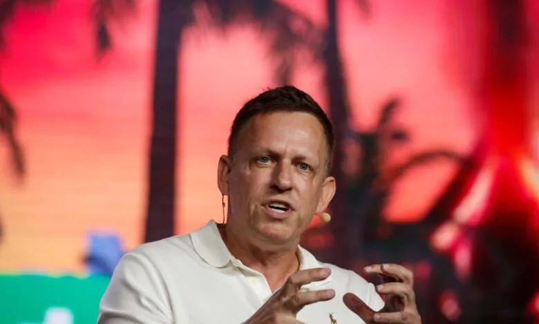 Peter Thiel speaking on stage with a vibrant tropical background.