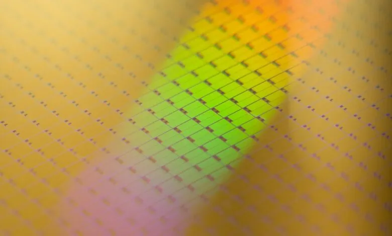 Close-up of a silicon wafer with microchips, showing a grid pattern and iridescent colors.