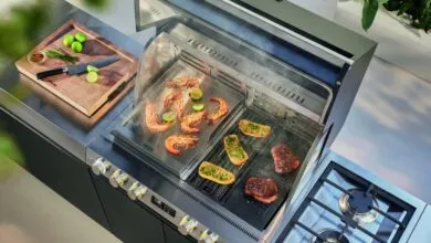 Overhead view of a modern outdoor kitchen grilling shrimp, steak, and garlic bread.