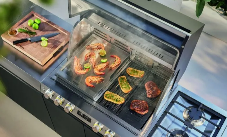 Overhead view of a modern outdoor kitchen grilling shrimp, steak, and garlic bread.