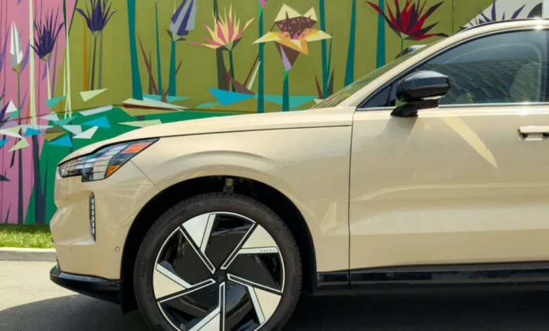Beige Volvo EX90 electric SUV parked near vibrant mural.