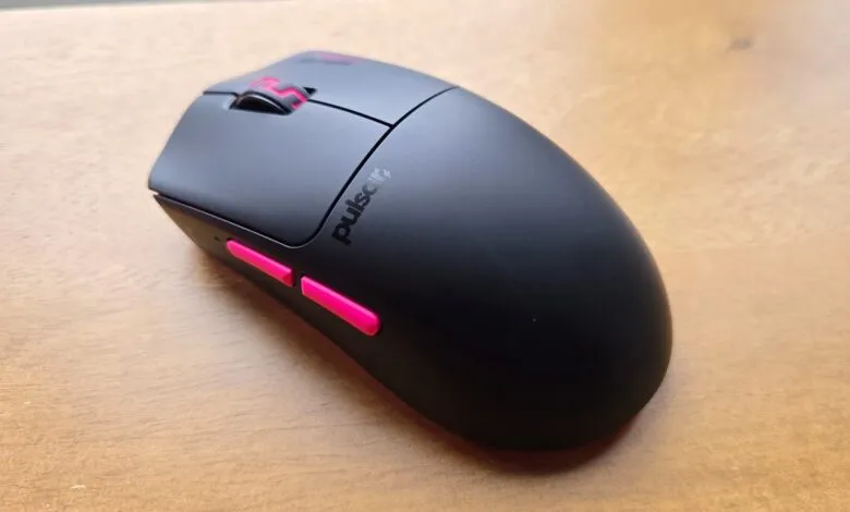 Black Pulsar gaming mouse with pink accents on a wooden surface.