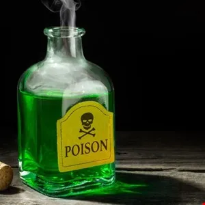 A glass bottle of bright green liquid with a skull and crossbones poison label, emitting steam.