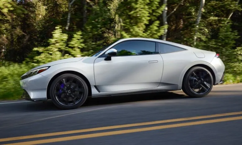 Sleek silver Honda Prelude driving on a scenic road.