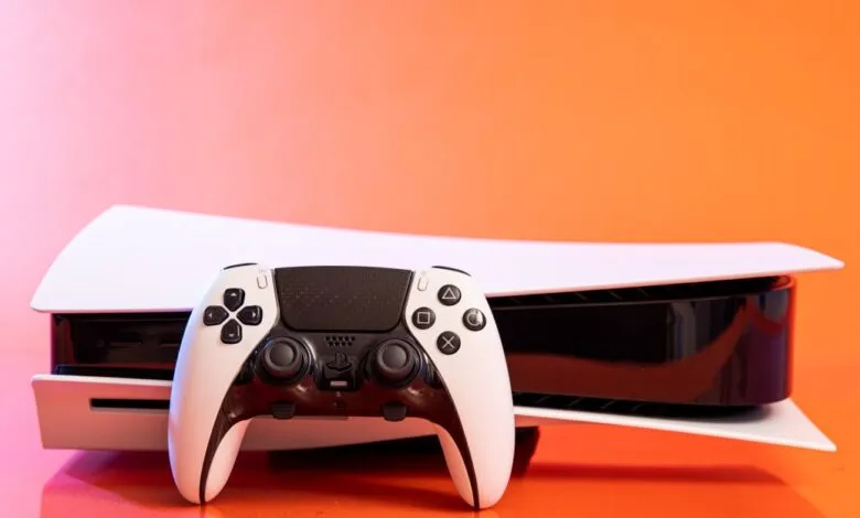 Sony PlayStation 5 console with its DualSense Edge controller, shown against a vibrant orange background.