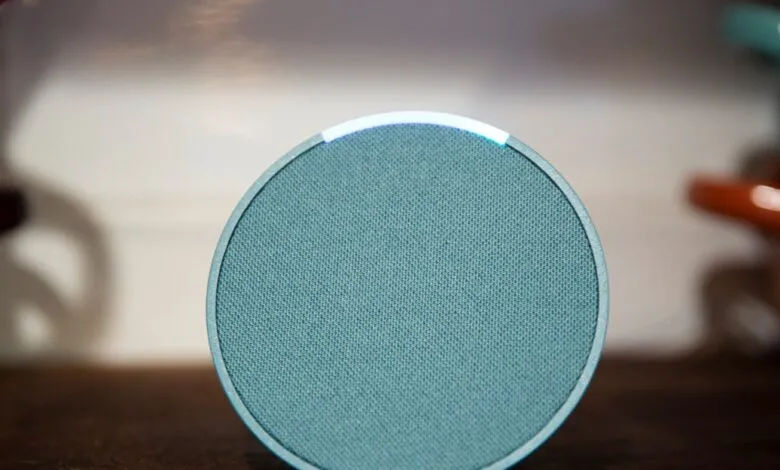 Close-up of a teal Amazon Echo Pop smart speaker with a glowing blue light ring.