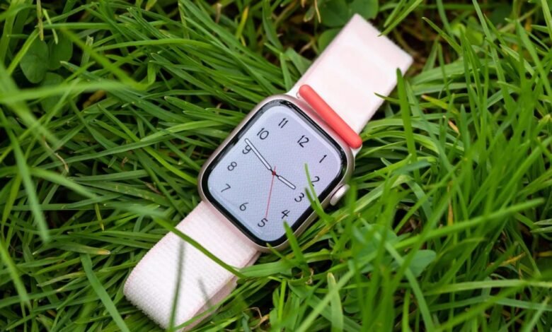 Apple Watch Ultra with pink band rests in green grass.