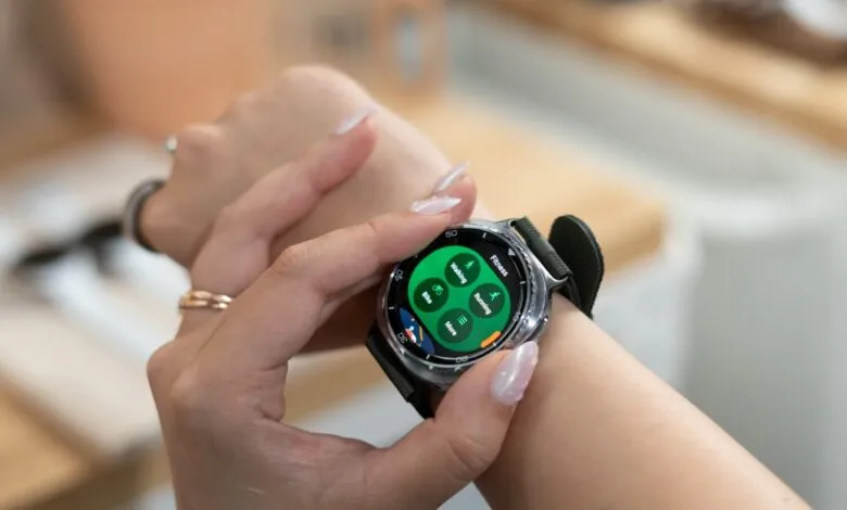 Close-up of a woman's wrist wearing a Samsung Galaxy smartwatch, displaying a fitness tracking interface.