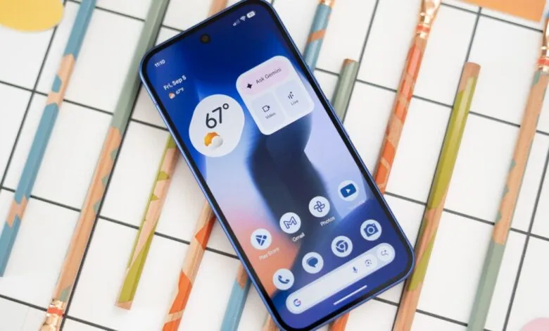 Blue Google Pixel smartphone displaying its home screen with weather and apps, surrounded by colorful pencils.