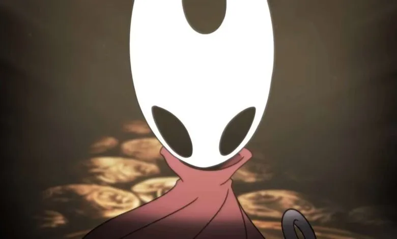 Close-up of Hornet from Hollow Knight: Silksong, a white mask with dark eyes, wearing a pink cloak.