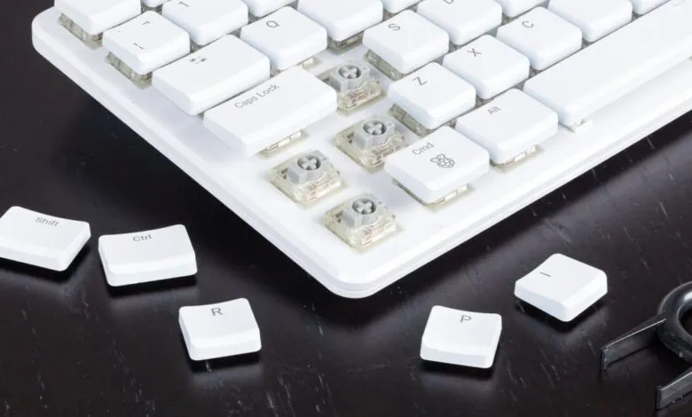 Close-up of a white mechanical keyboard with keycaps removed, showing switches and a keycap puller.