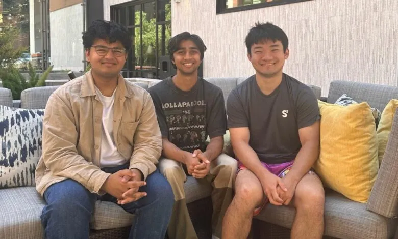 Three young men smiling, sitting together on an outdoor couch.