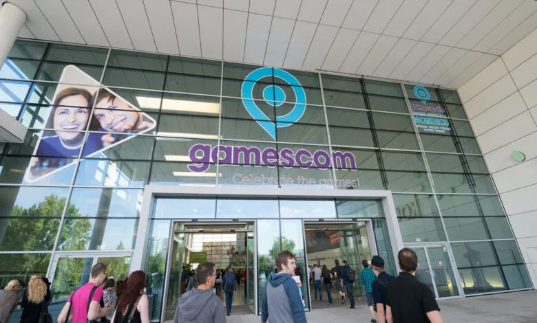 Gamescom entrance with attendees entering the building. The Gamescom logo is prominently displayed.
