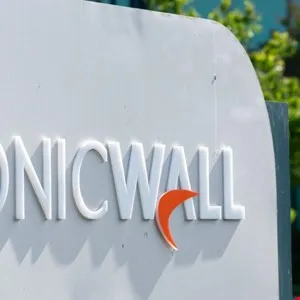 Close-up of the SonicWall logo on a white sign with green foliage in the background.