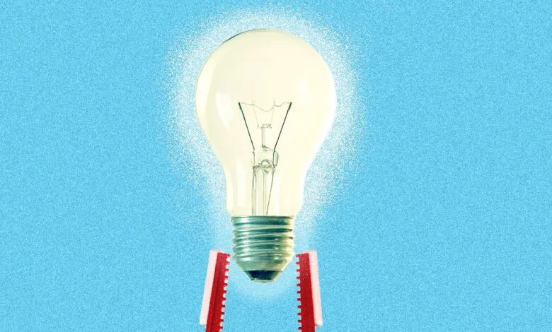 Lightbulb held by red clips against a blue background, symbolizing a new idea.