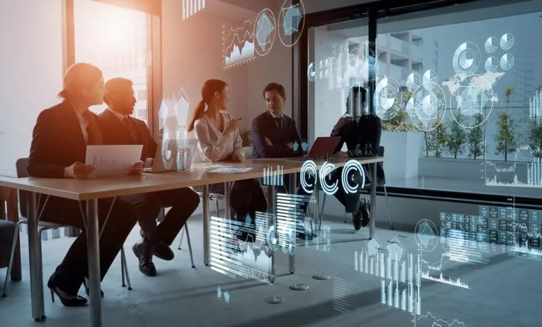 Business team collaborates around a table, analyzing data projected as holographic charts and graphs.