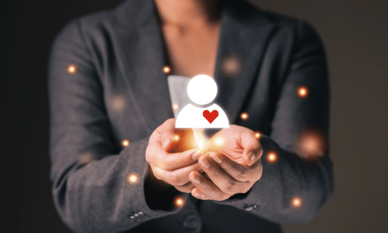 Person's hands gently cradling a glowing icon of a person with a heart, symbolizing human-centered approach.