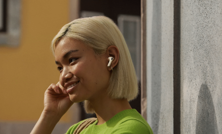 Woman wearing white AirPods Pro earbuds, smiling outdoors.