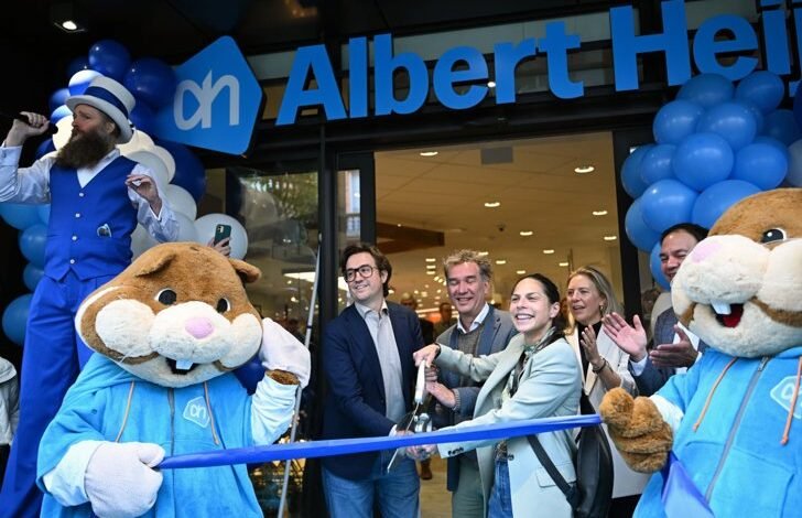 Albert Heijn store grand opening in Leuven, Belgium, with mascots, staff, and guests cutting a ribbon.