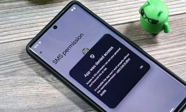 Smartphone screen showing an SMS permission denied notification with a small Android mascot figure in the background.