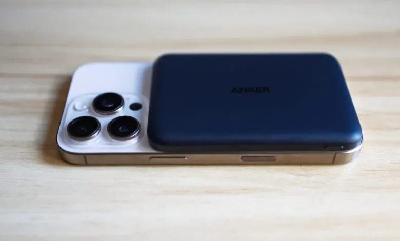 Anker Nano power bank on top of an iPhone, both on a wooden surface.