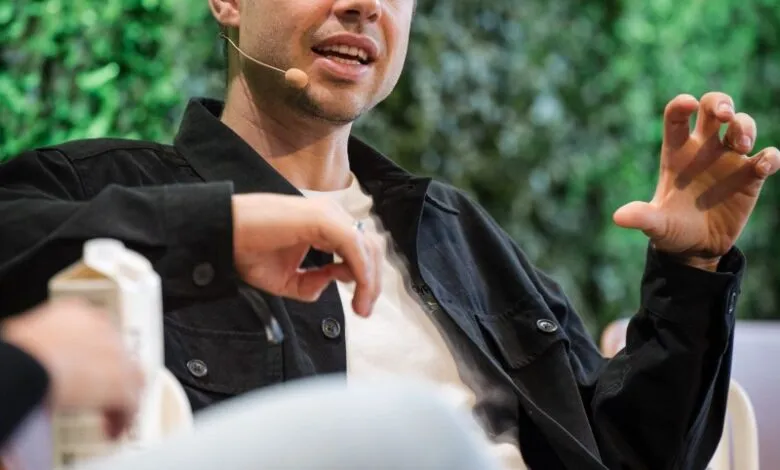 Anton Osika, a young man with brown hair, speaks at a conference, wearing a black jacket and white shirt.