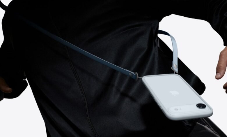 iPhone in a light gray case with a blue crossbody strap.