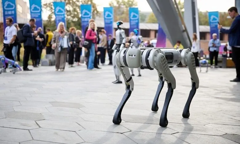 Quadrupedal robot at tech conference, grey and white, outdoors.