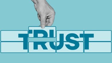 Hand placing a puzzle piece completing the word TRUST. Teal and white color scheme.